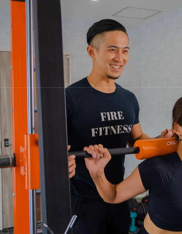 岡山のパーソナルジムFIREFITNESSの店内で、トレーナーがスクワットを指導している様子
